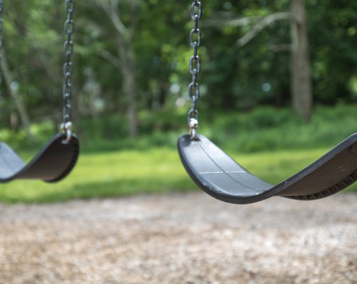 An empty pair of swings hang at the playground.
